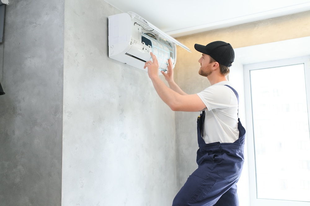 Técnico abriendo una unidad interior de aire acondicionado en una vivienda para revisarla